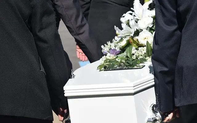 Bílá rakev s květinami při pohřbu